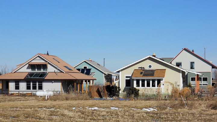 81.jpg - On the southern roofs of these EcoVillage houses solar collectors heat both houses and water. Well-shaded southern windows warm the houses in winter, but protect them from hot summer sun.