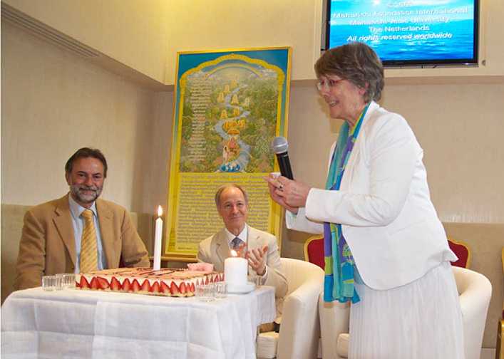France_03_GMDO-Nat.-Dir.jpg - France: The National Director of France for the Global Mother Divine Organization, Fariza Baum, read an inspiring message of congratulations from their leaders, Dr Michael Dillbeck (centre), Dr Susie Dillbeck and the Raj Rajeshwari for France. She lit a candle on a celebratory cake and led the audience in renewing their wishes for everyone?s well-being and the success of the newly formed Veda Club, established for inspiring a healthy lifestyle in harmony with Natural Law and invincibility for the country.