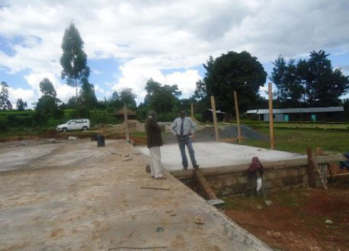 kenya11.jpg - Organizers of the construction team examine the slab floor and discuss the next steps, in preparation for erecting the walls.