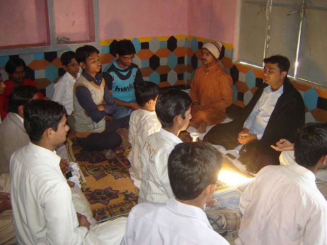 Group-meditation.jpg - Dr Kumar, centre right, conducts a weekly group meditation in a Pakistani village. In any village or town where people have learned Transcendental Meditation the Kumars arrange a weekly group meditation. Once a week practitioners connect with Dr Kumar on Skype to refresh their knowledge.